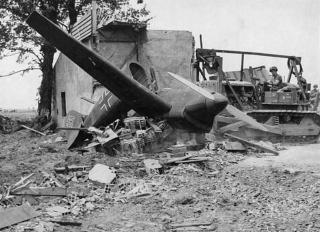 Imagine atasata: A bulldozer from the 9th Air Force engineers clears a German dummy plane from a captured airfield on the Cherbourg peninsula of France. (Small) (2).jpg
